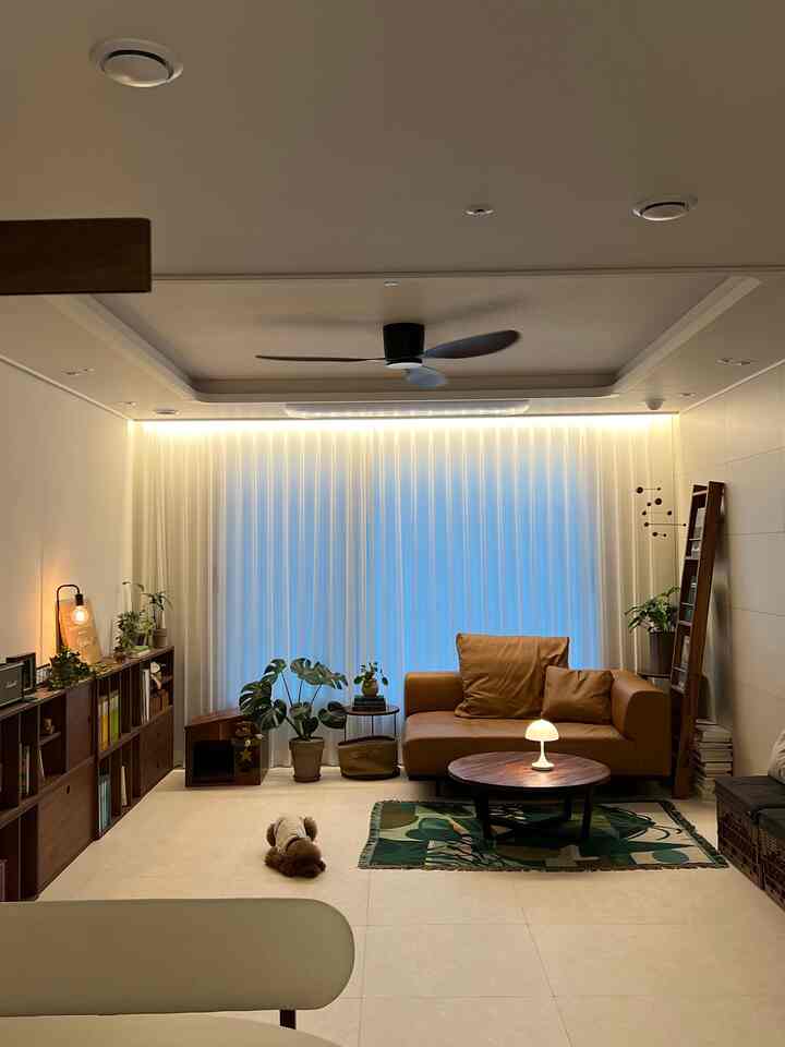 ブラウンのレザーソファと木製家具が配置されたホワイトトーンのリビング、床に犬が横たわり自然な雰囲気のあるインテリア