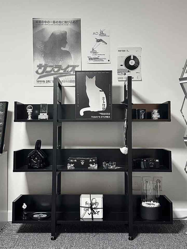 黒とシルバーのトーンが特徴的なモダンなリビングルーム、中央に黒のスチール製本棚と猫のシルエットのポスターが配置された洗練された空間