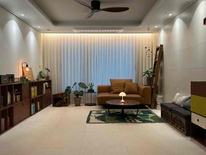 温かみのあるナチュラルカラーのリビング、レザーソファと本棚が配置され、読書とくつろぎのある印象的な空間