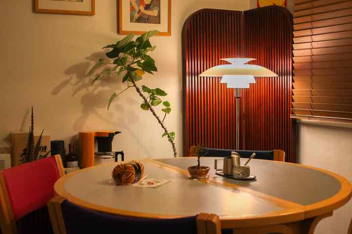 ナチュラルな木目調と暖色照明が調和するダイニングルーム、丸いダイニングテーブルと間仕切りが配置された雰囲気のある空間