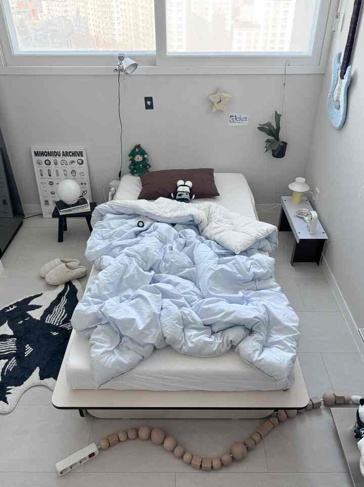 白い壁と床、スカイブルーの掛け布団が置かれた中央にベッドのあるモダンな寝室空間