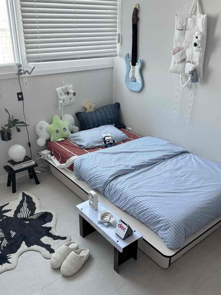 ホワイトとブルーのトーンの一人暮らし用寝室、壁に寄せたベッドが配置され、ミニマルでナチュラルモダンな雰囲気のあるインテリア