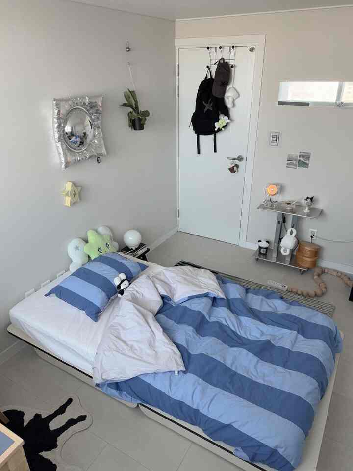 ナチュラルカラーとブルーの寝具が調和した一人暮らしの寝室、シンプルで居心地の良い空間