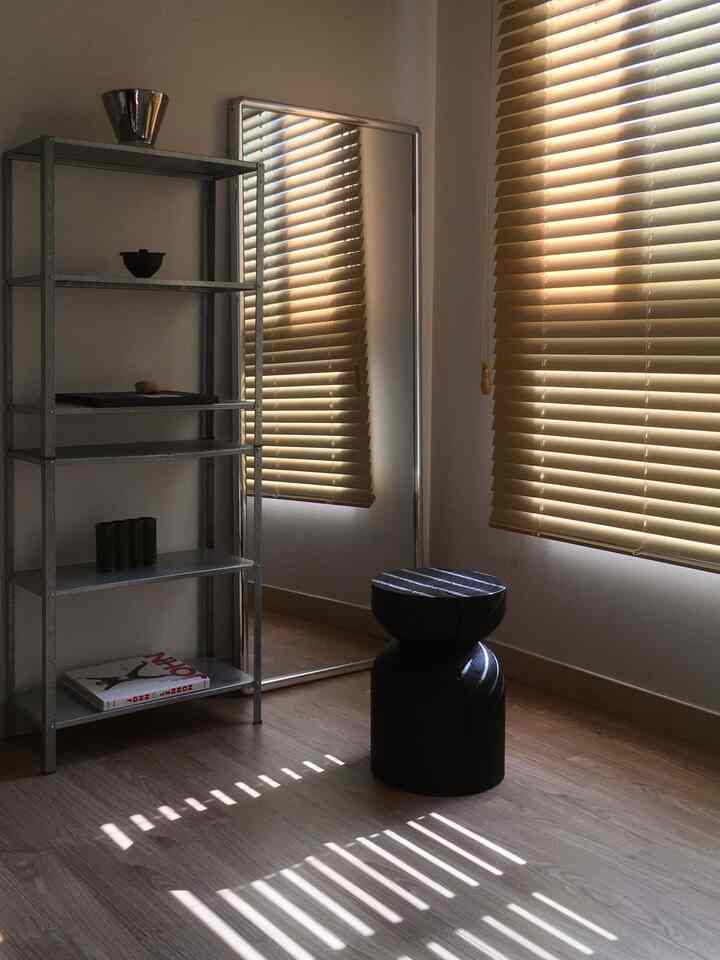 暖かい木目調とメタル棚、ブラインドが配置された小さな居心地の良い部屋