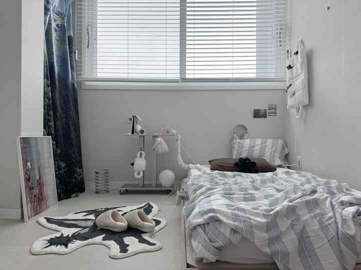 ベージュと白の色調の寝室、ロータイプのベッドとブラインド、カーテンが配置された落ち着いた雰囲気のインテリア