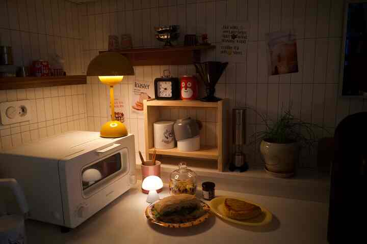 温かみのある照明が灯るナチュラルカラーのキッチン、トースターとテーブルランプが配された雰囲気の良い空間