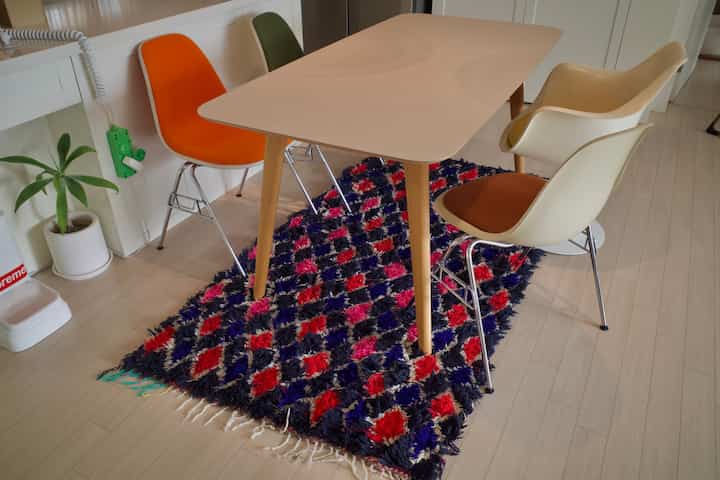 ナチュラルな木目調の床とヴィンテージのアームチェアが配置されたダイニング、モロッコ風ラグがアクセントの温かみのある空間