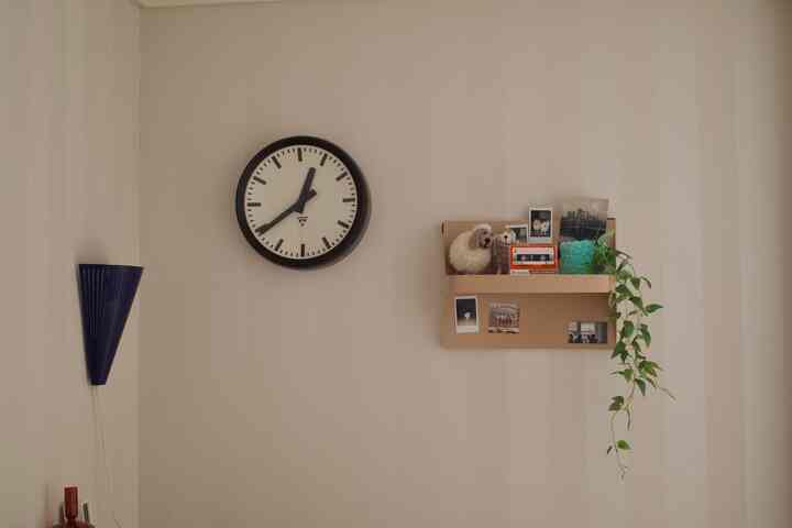 ネイビーブルーとベージュのトーンのヴィンテージ壁面照明と棚、オレンジのカセットスピーカーがアクセントの落ち着いた雰囲気のリビング壁面