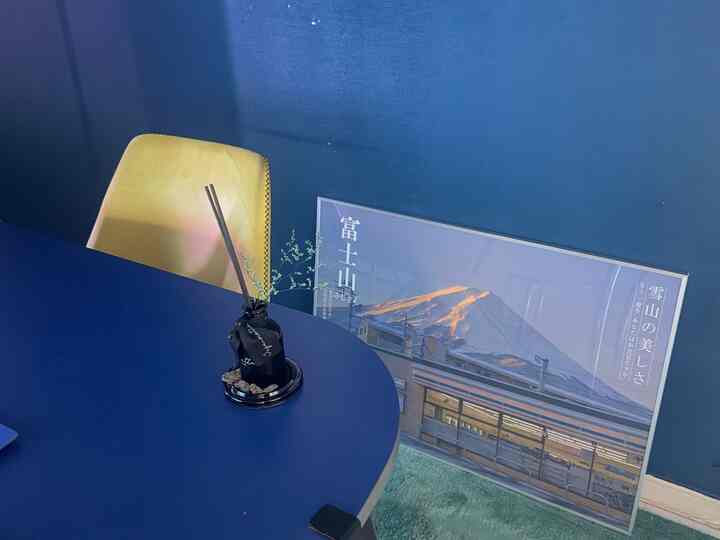 濃いブルーの壁とテーブル、黄色い椅子と額縁が配置されたおうちカフェの雰囲気のあるインテリア