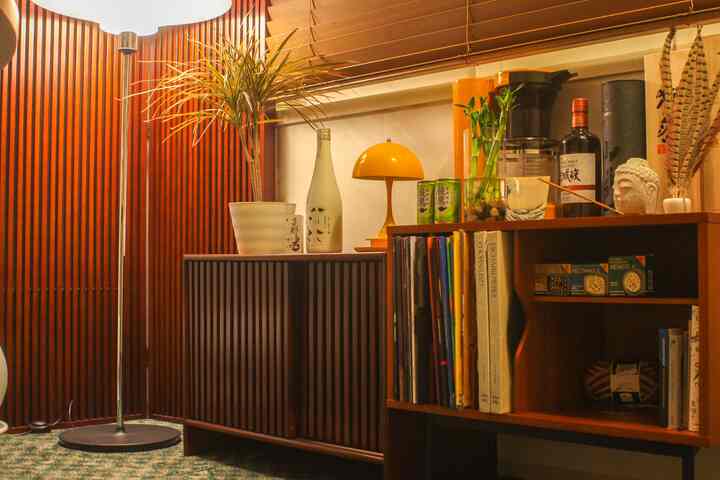 ダークブラウンの落ち着いたトーンとグリーンのラグが調和する、ヴィンテージ家具と植物が配置されたキッチンの印象的な空間