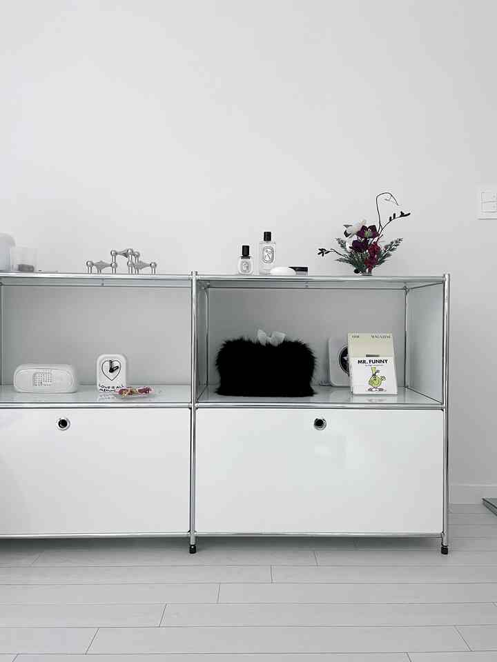 白とメタルフレームのキャビネットが配置されたモノトーンの室内、シンプルで洗練されたインテリア空間