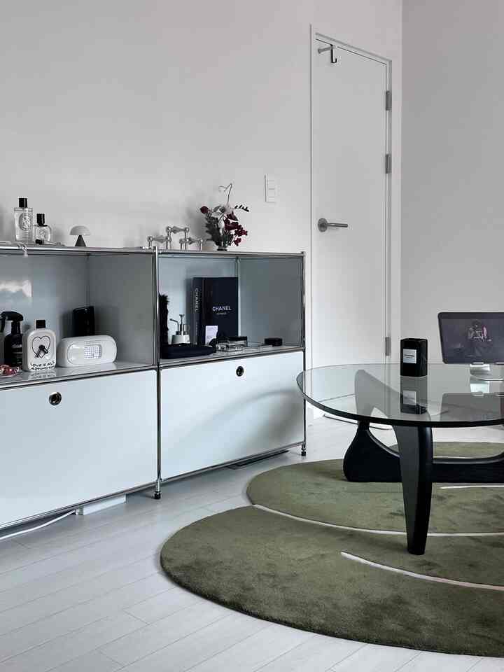 白と緑の色調のリビングルーム、ガラスコーヒーテーブルと収納キャビネットが配置されたモダンで清潔感のあるインテリア