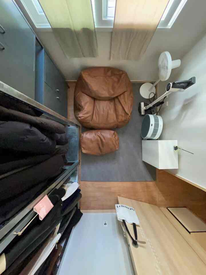 白い壁と茶色のビーズクッションがあるコンパクトな部屋、シンプルで居心地の良い雰囲気