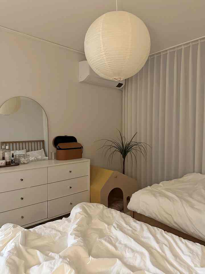 ベージュと白のトーンの寝室、二つのシングルベッドと化粧台、ペットハウスが配置された雰囲気のある空間