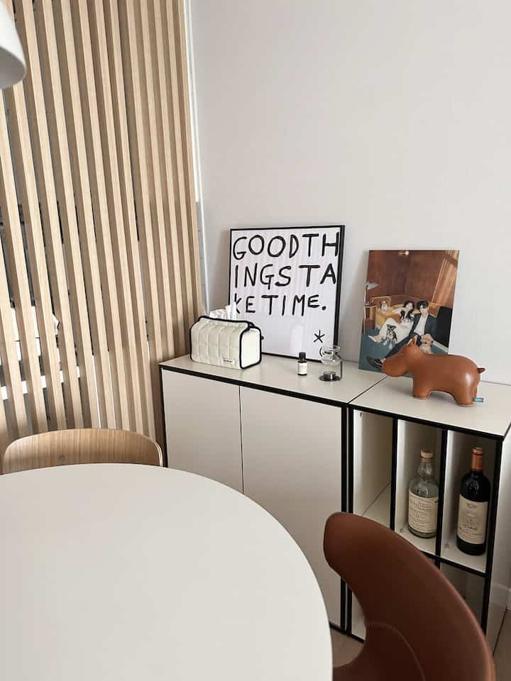 ホワイトとブラウンのトーンが特徴のリビング横収納と円形テーブルが配置されたモダンなインテリア