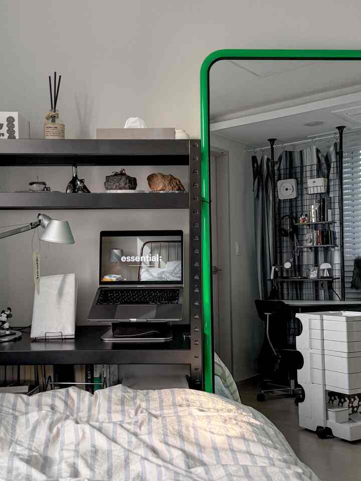 ホワイトとグリーンの色調の寝室、ホームオフィスの設備と大型の鏡が配置された実用的でコンパクトな空間