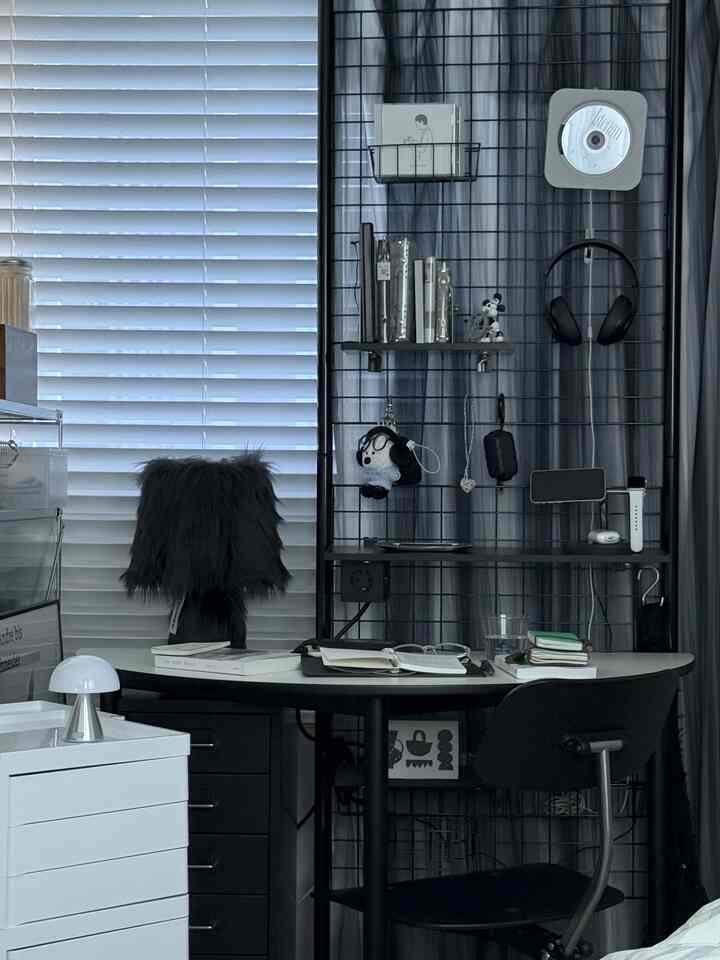 白と黒のトーンの狭い部屋、金属のパーティションと机、オフィスチェアが配置された印象的なホームオフィス空間