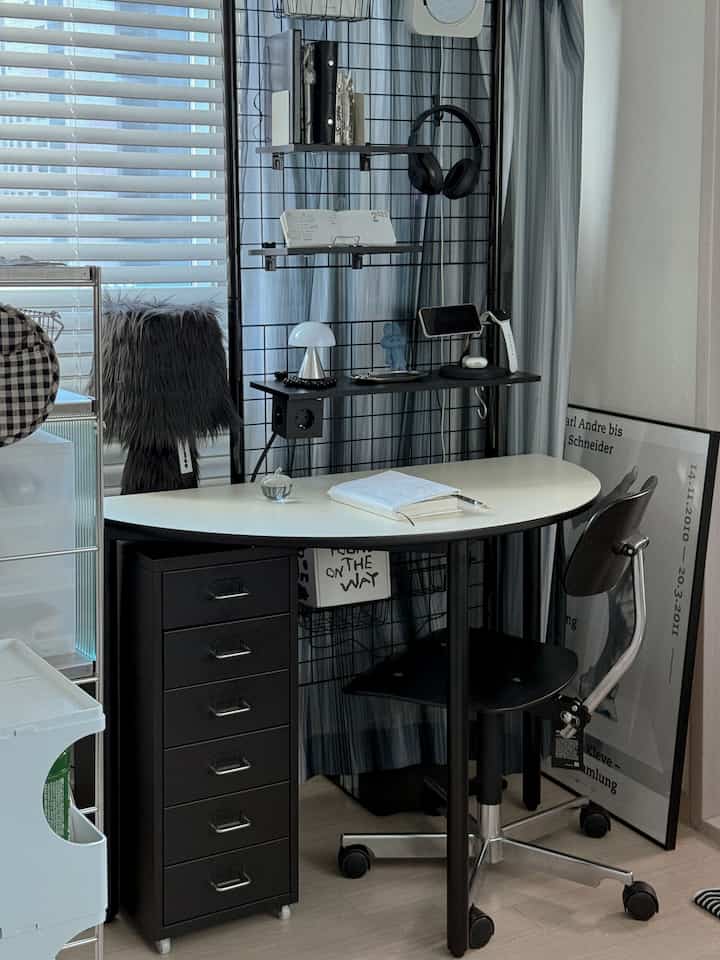 黒と白を基調としたホームオフィス、白い半円形のデスクと黒い引き出しキャビネット、オフィスチェアが配置された整ったワークスペース