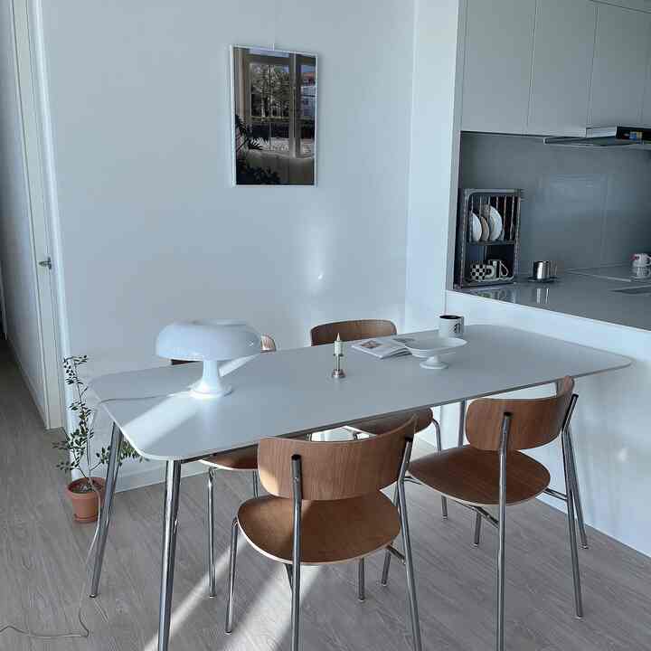 白とナチュラルウッドの調和が美しいダイニング、シンプルでモダンなテーブルと椅子が配置された雰囲気のある空間