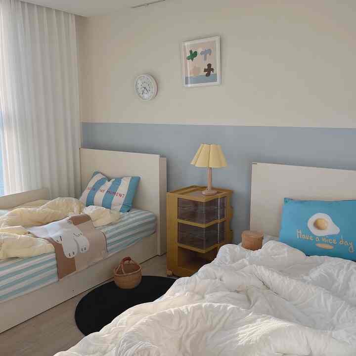 黄色と青のトーンで装飾された子供部屋、白いベッド2台と黄色の収納棚、可愛らしい小物が配置された温かなインテリア