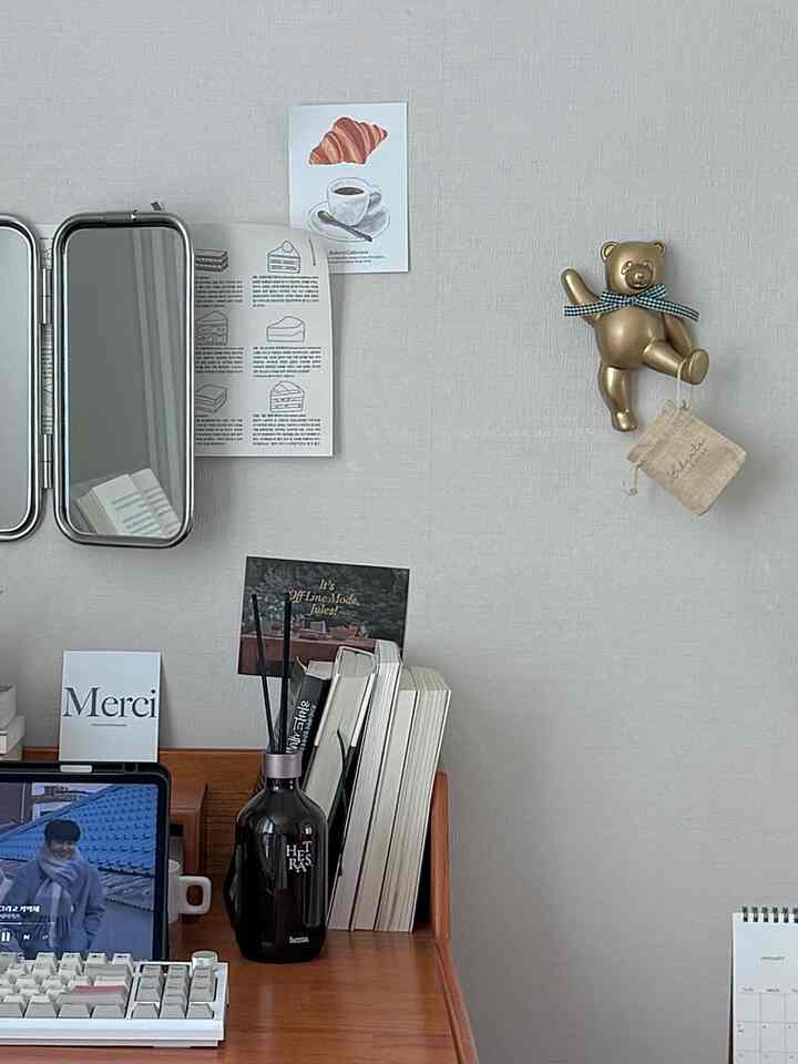 ナチュラルなデスクスペース、ニュートラルな壁にゴールドのくまの壁掛けフックが配置された印象的なインテリア