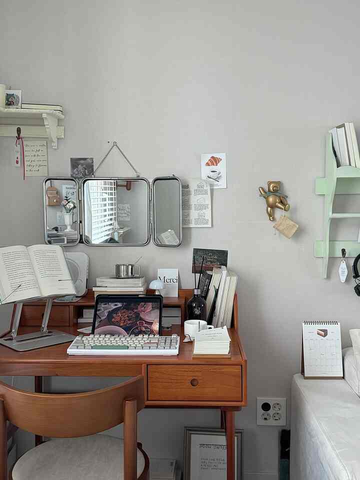 白い壁と茶色の木製デスク、三面鏡と本棚が配置されたモダンなホームオフィスのインテリア