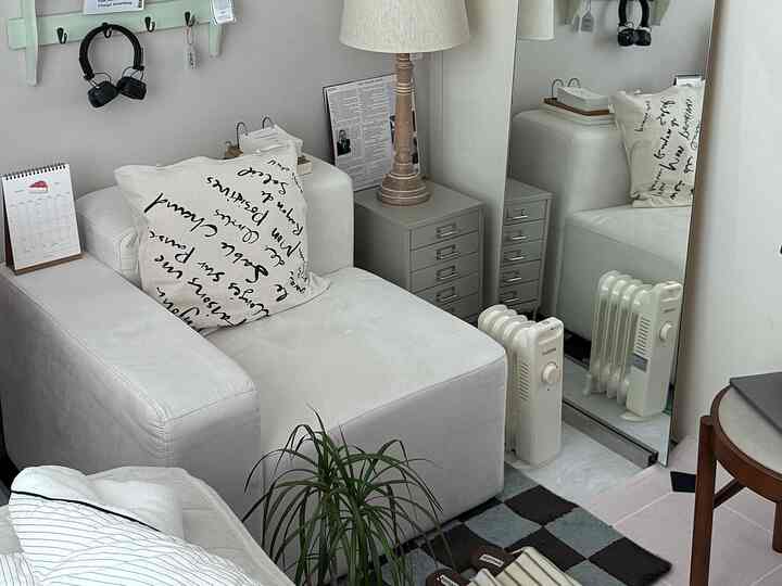 白とグレーのトーンのリビング、シンプルでナチュラルなソファと木目調のフロアランプが配置された雰囲気のある空間