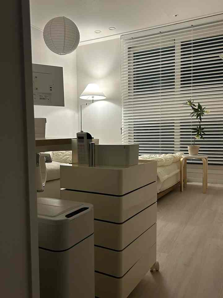 ホワイトとウッドトーンが調和したコンパクトな一人暮らしのホームオフィス空間、すっきりとした収納と自動センサーごみ箱があるシンプルモダンなインテリア