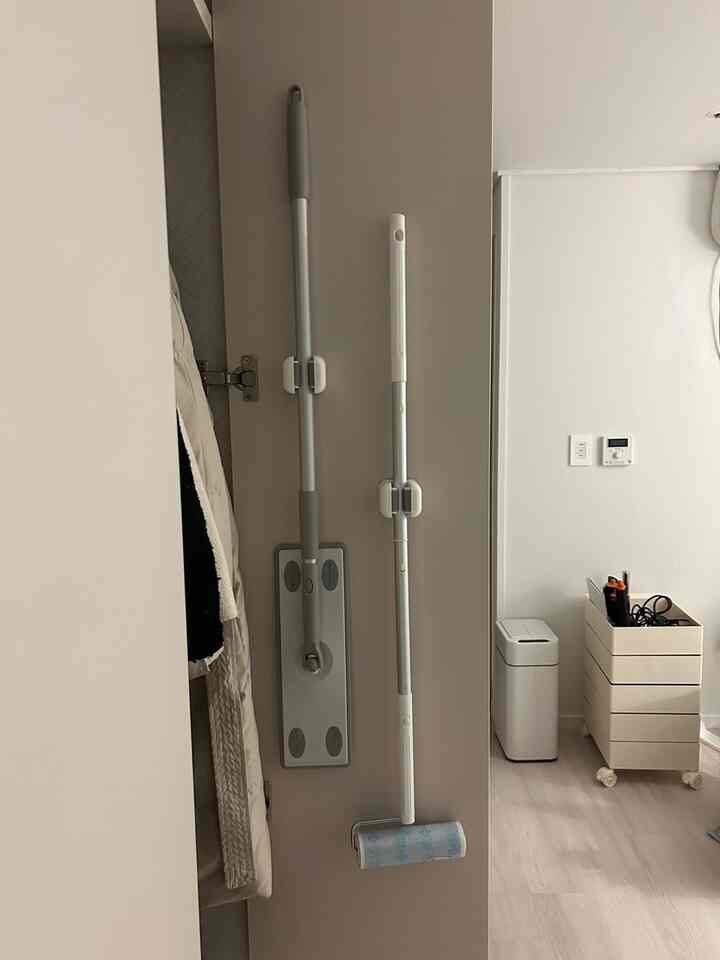 ホワイトとグレーのトーンで統一されたビルトインクローゼットの内部にきちんと取り付けられた掃除道具があるコンパクトで整理された空間