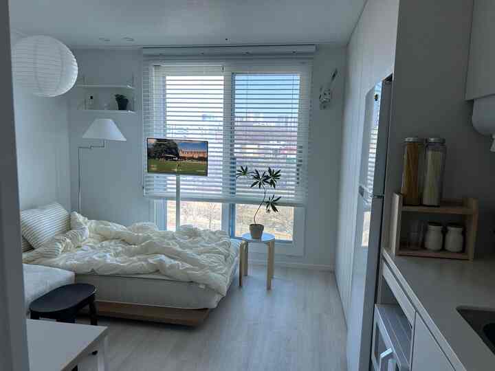 白を基調としたワンルームの寝室とキッチンが配置されたシンプルで清潔感のあるインテリア