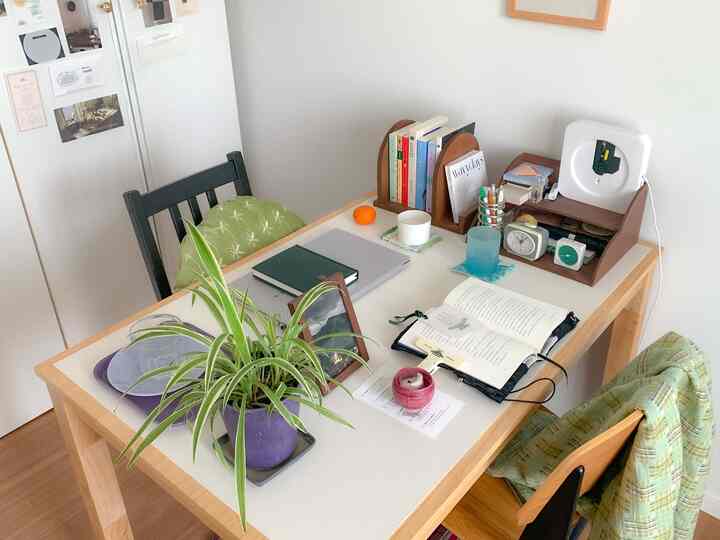 白と木目調の2人用ダイニングテーブル空間、本とノートパソコンが置かれ、在宅勤務とおうちカフェの雰囲気が感じられるシンプルなインテリア