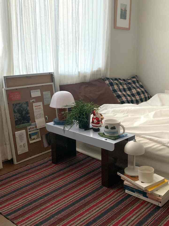 白い寝具と赤いストライプのカーペットが配置された寝室、シンプルで暖かみのある雰囲気