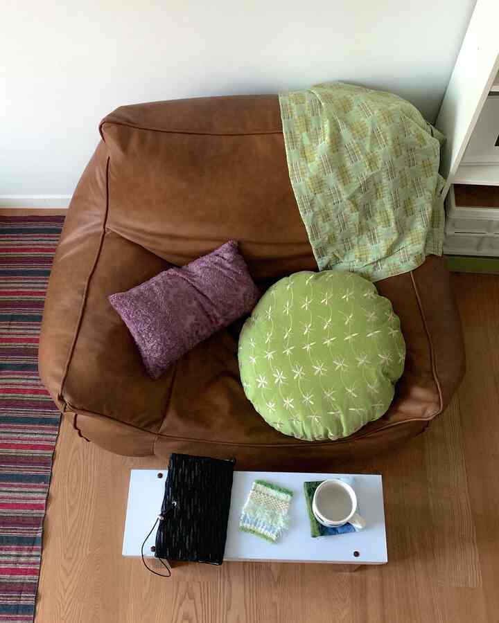 柔らかいブラウンのビーズクッションソファと様々なクッションが配置されたリビングルーム、木目調の床と白いサイドテーブルが調和した雰囲気のあるインテリア