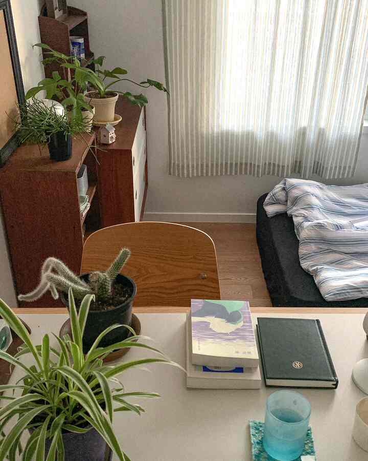 黄色とスカイブルーのストライプカーテンがある6畳の寝室、木製家具と植物が配置されたナチュラルな雰囲気のインテリア