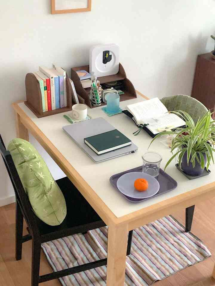 白と木目調の調和した二人用ダイニングスペース、本と植物が配置された雰囲気のあるインテリア