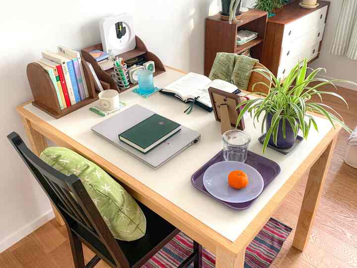 ホワイトとウッドトーンのコンパクトな部屋、デスクと2脚の椅子、本と植物が配置された居心地の良いホームオフィス