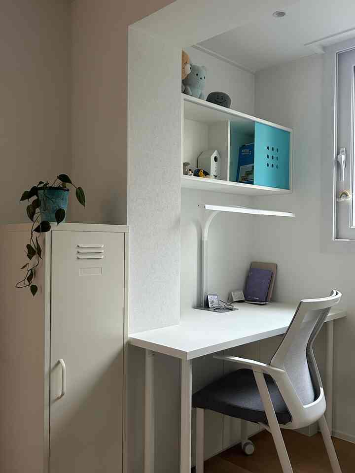 白を基調とした小さなホームオフィス、デスクとオフィスチェアが整然と配置されたモダンな雰囲気の部屋