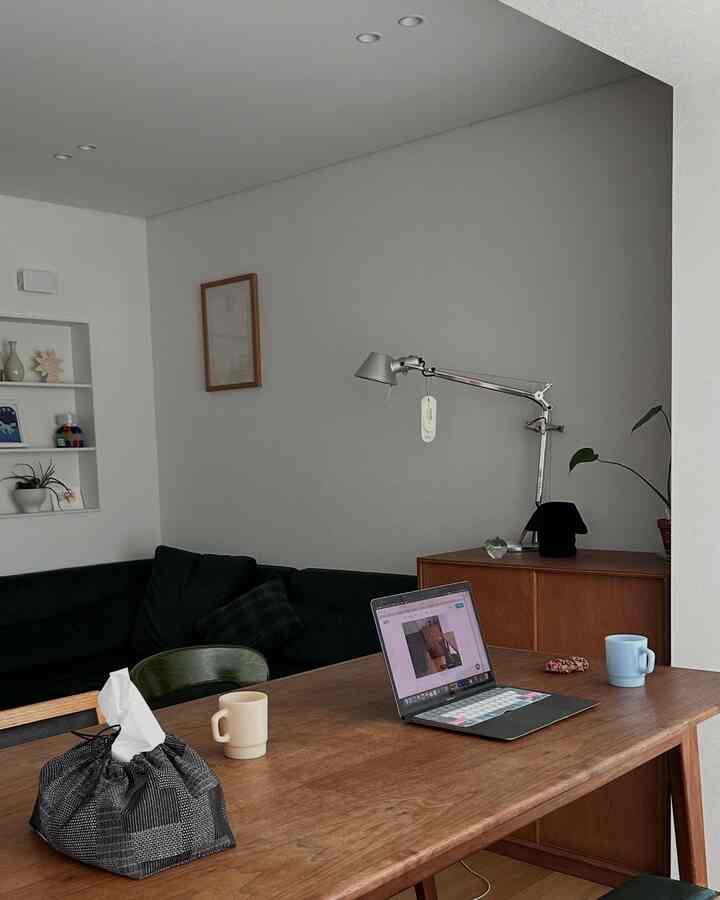 ナチュラルな木目調とグリーンソファが調和したダイニング、ノートパソコンとテーブルランプが配された雰囲気のあるホームオフィス空間