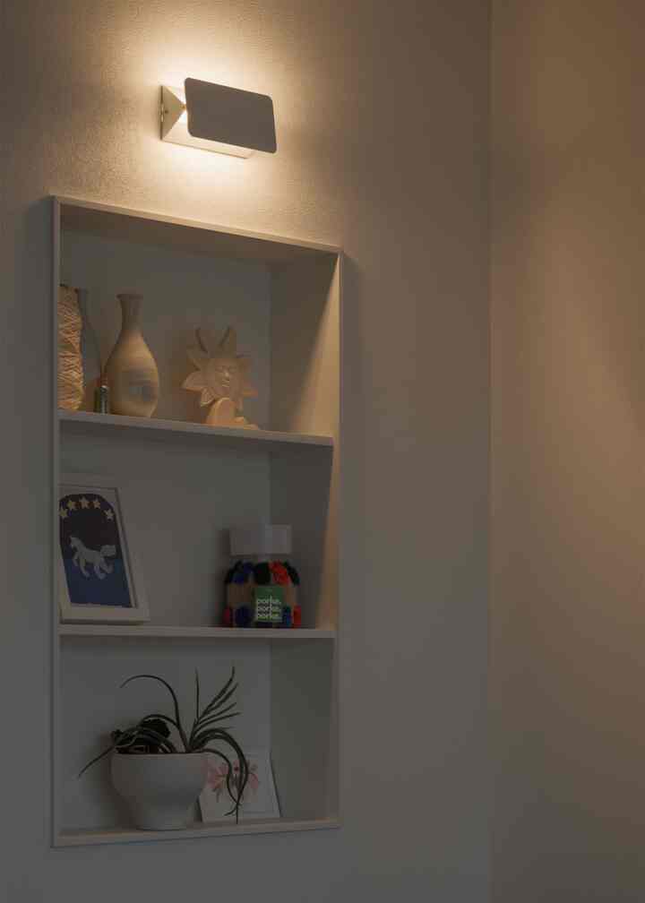 温かい光の白い壁の棚に装飾品が置かれたミニマルな雰囲気のインテリア