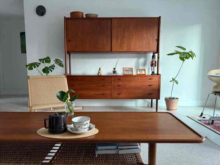 ナチュラルな木目調とラタンが配された北欧スタイルのリビング、チーク材のテーブルとキャビネットが印象的な落ち着いた空間