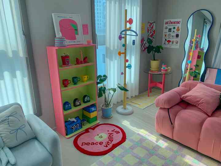 白い壁とピンクのソファ、カラフルな小物とラグが映える活気のあるリビングスペース