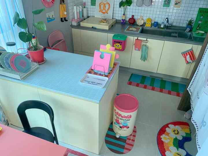 明るい黄色とピンクが調和するキッチン、カラフルな小物とセルフ施工のシートが印象的なインテリア