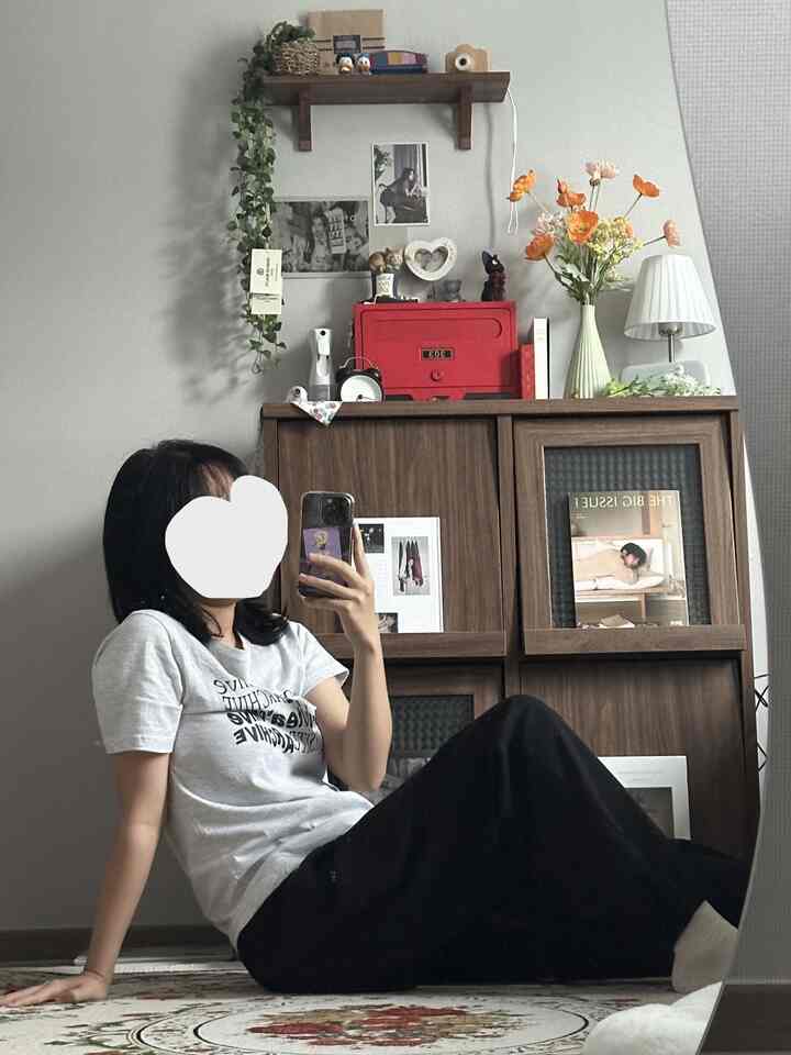 グレーの壁と木目調のキャビネットが中心のリビング、赤い郵便箱と花瓶がアクセントのシンプルでナチュラルなインテリア