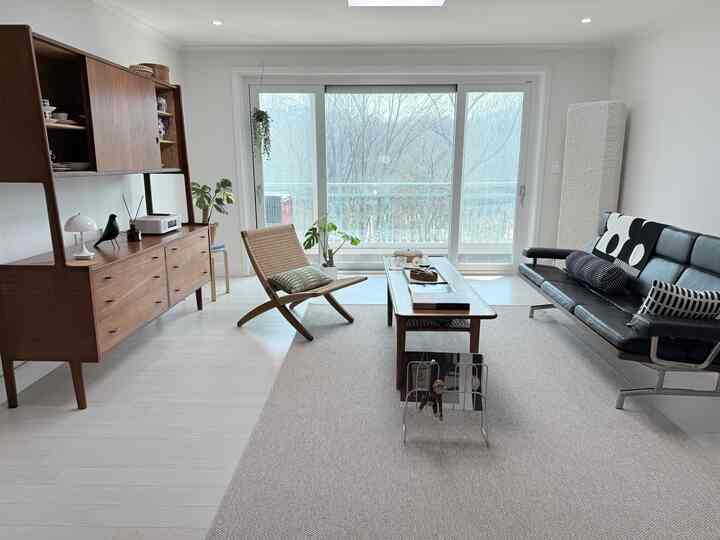 白い壁と床にナチュラルブラウンの家具とソファが配置された北欧スタイルのリビング