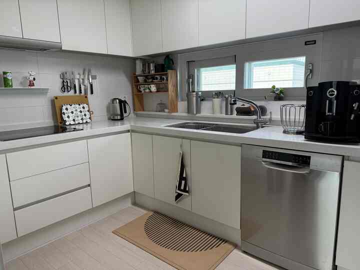 明るく清潔感のある白を基調としたキッチン、ステンレス製の家電と木製の棚が調和したモダンな雰囲気