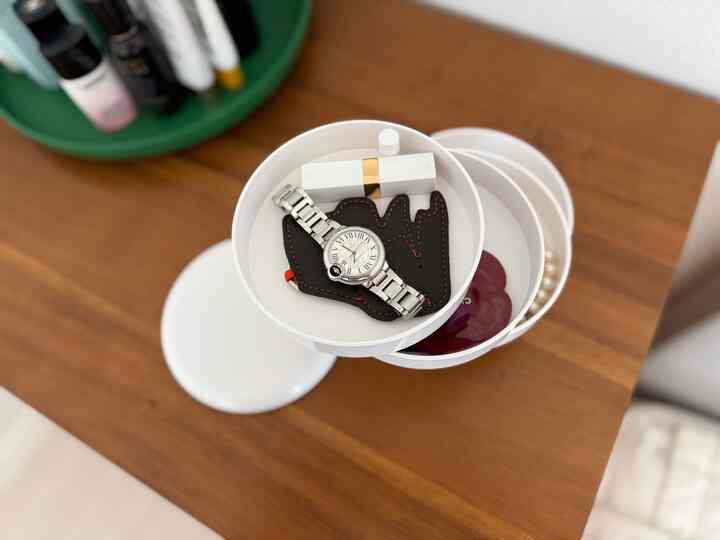 白と木目調の調和がある空間、回転式収納と時計が整然と配置されたシンプルな化粧台の様子