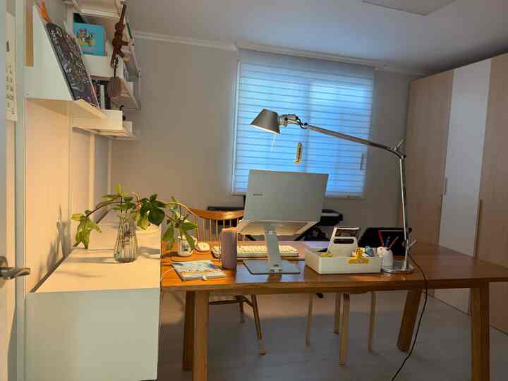 ホワイトと木目調のホームオフィス、デスクとスタンドランプが配されたシンプルモダンなワークスペース