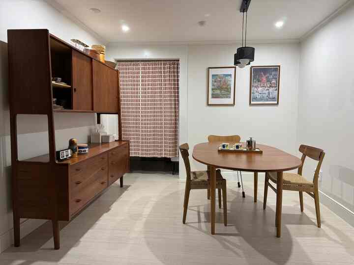 ナチュラルな色調のダイニング、木製のテーブルと椅子、大きなキャビネットが配置された温かみのある空間