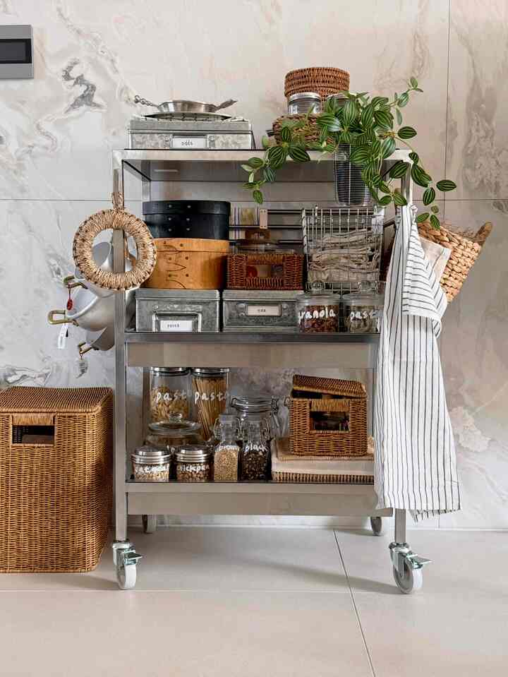 シルバーのステンレス製キッチンワゴンにラタンバスケットとガラス瓶が整頓されたナチュラルトーンのキッチン収納スペース