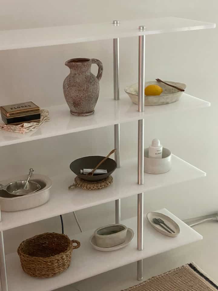 白とシルバーのトーンで統一されたモダンな棚とナチュラル素材のオブジェが配置された印象的なインテリア